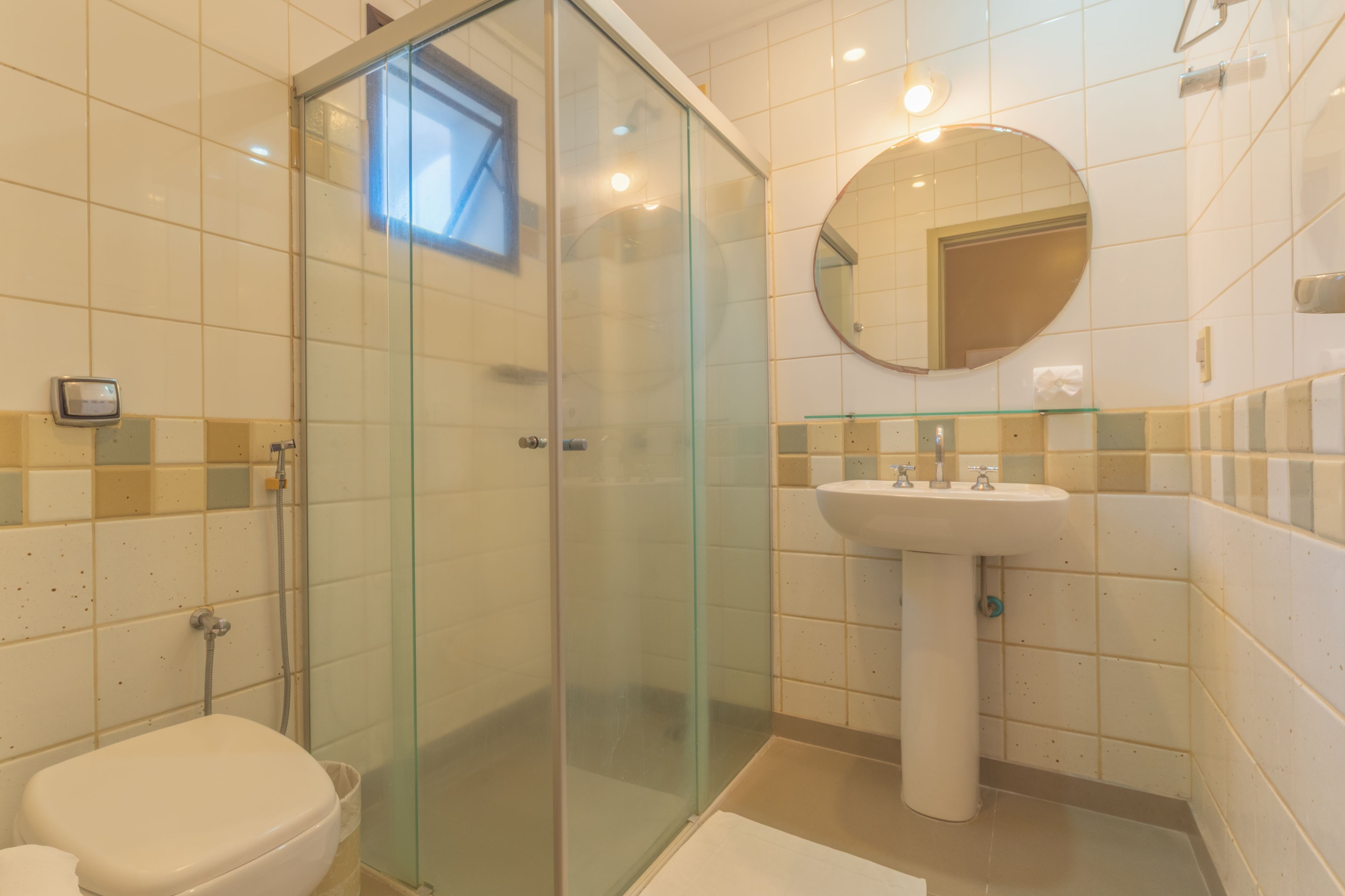 A bathroom with a glass-enclosed shower, a white sink, and a toilet.