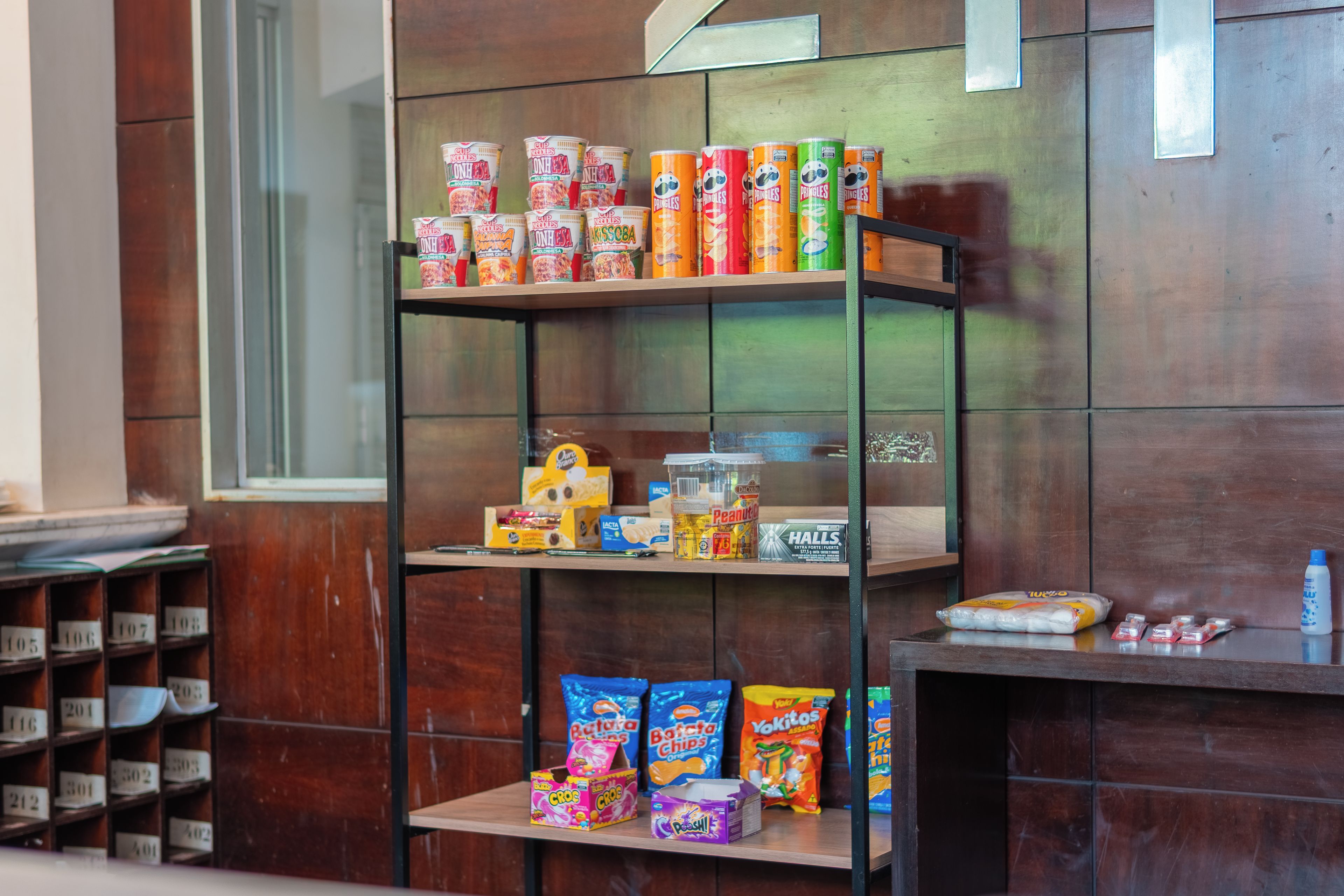 A shelf stocked with various snack items including chips, cookies, and canned goods.