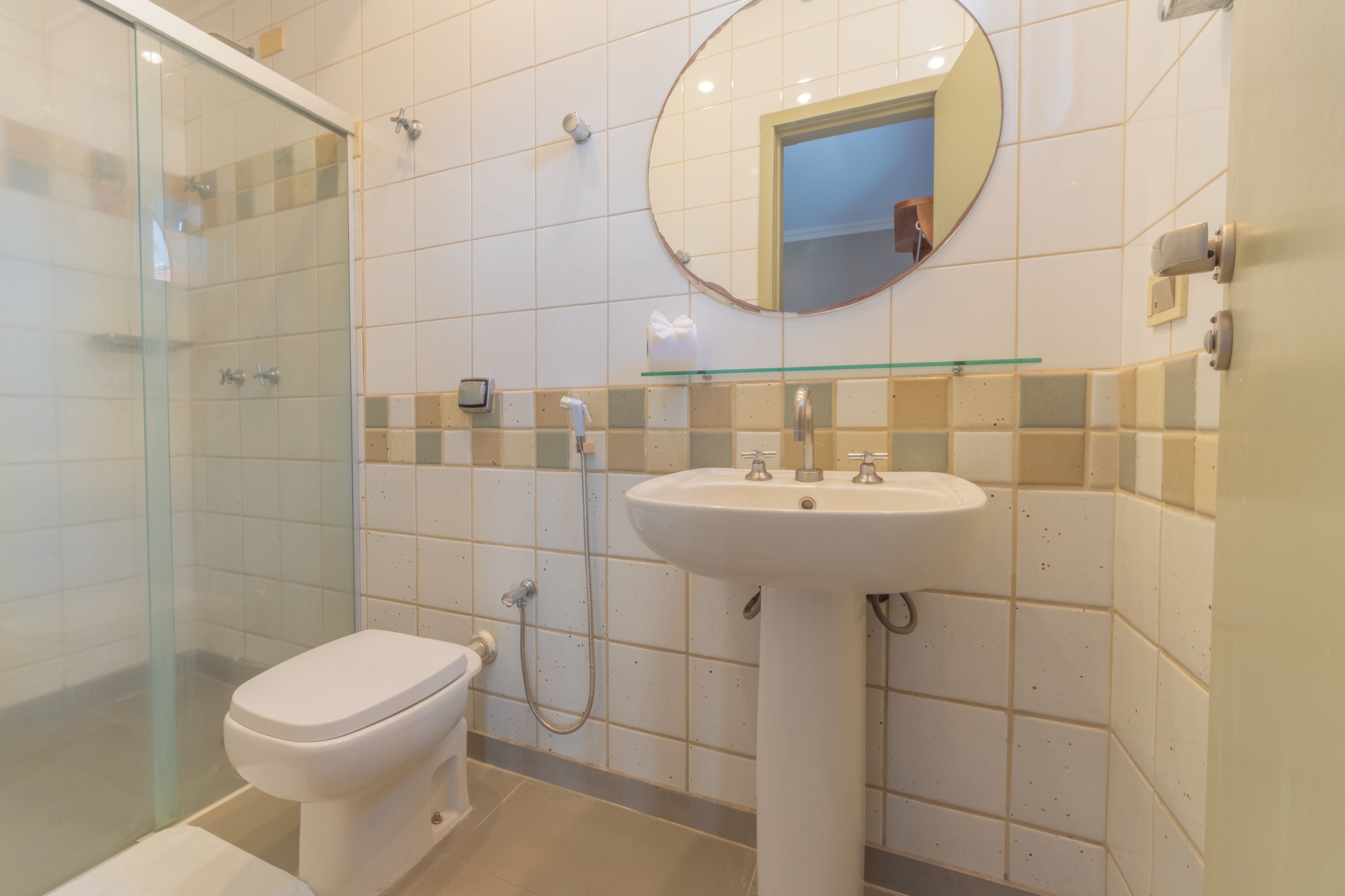 Une salle de bain comprenant des toilettes, un lavabo, une douche en verre et un miroir au mur.