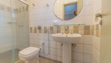 Une salle de bain comprenant des toilettes, un lavabo, une douche en verre et un miroir au mur.