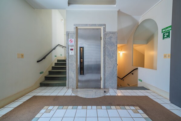 Una scala con corrimano, un allarme antincendio e un cartello che indica il piano.