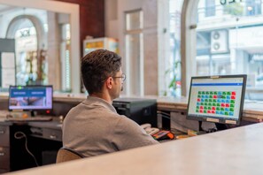 En person sitter vid ett skrivbord med två datorskärmar. På den ena visas ett färgstarkt gränssnitt och på den andra ett datorspel.
