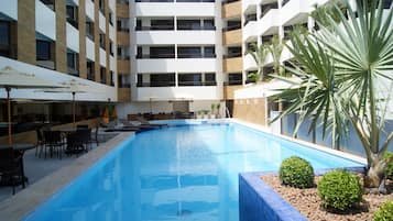 Una piscina al aire libre, sillones reclinables de piscina