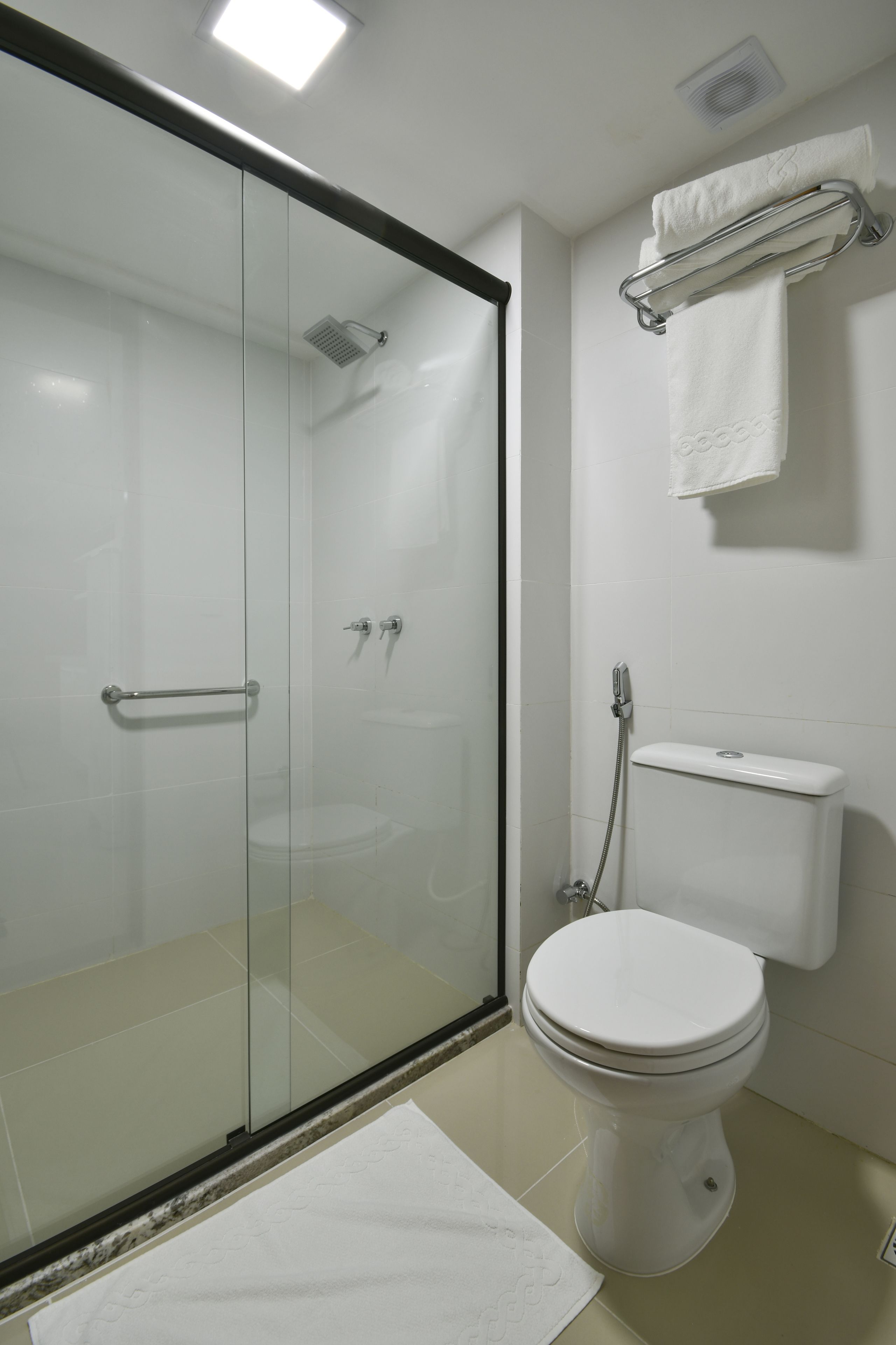 Un baño moderno con ducha de vidrio, inodoro blanco y toallero.
