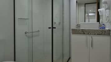 A modern bathroom with a glass shower enclosure, a white toilet, and a vanity with a mirror and countertop.