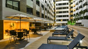 A hotel courtyard with outdoor seating, a pool, and a modern building facade. - Littoral Gold Flat (João Pessoa)
