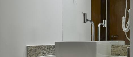 Ein Badezimmer mit einem weißen Waschbecken, einer Granit-Arbeitsplatte und einem an der Wand befestigten Föhn.