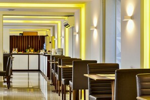 Un interior de restaurante moderno con una larga barra, varias mesas y sillas dispuestas en filas.