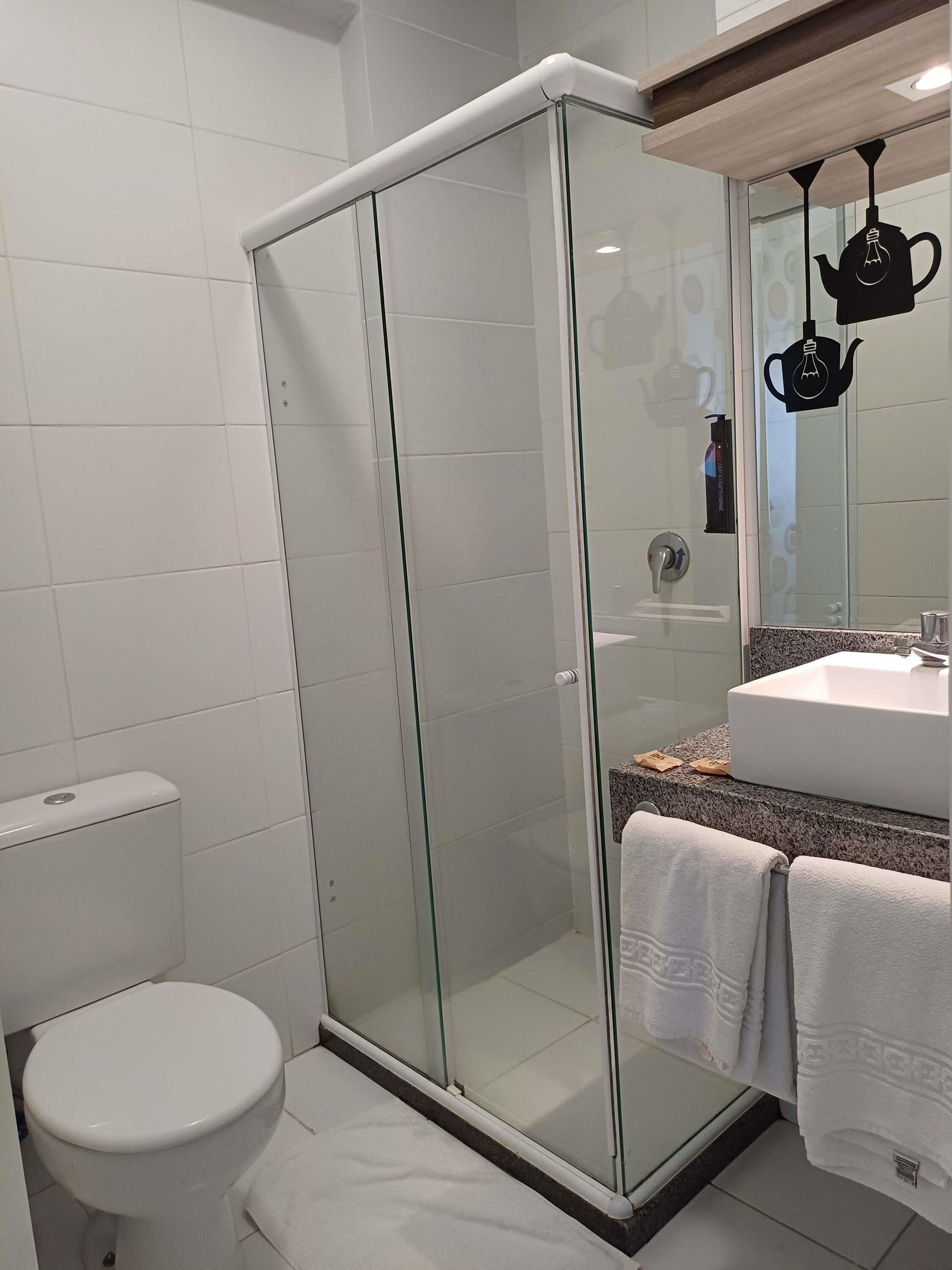Un baño moderno con ducha envuelta en vidrio, inodoro blanco y lavamanos con encimera.