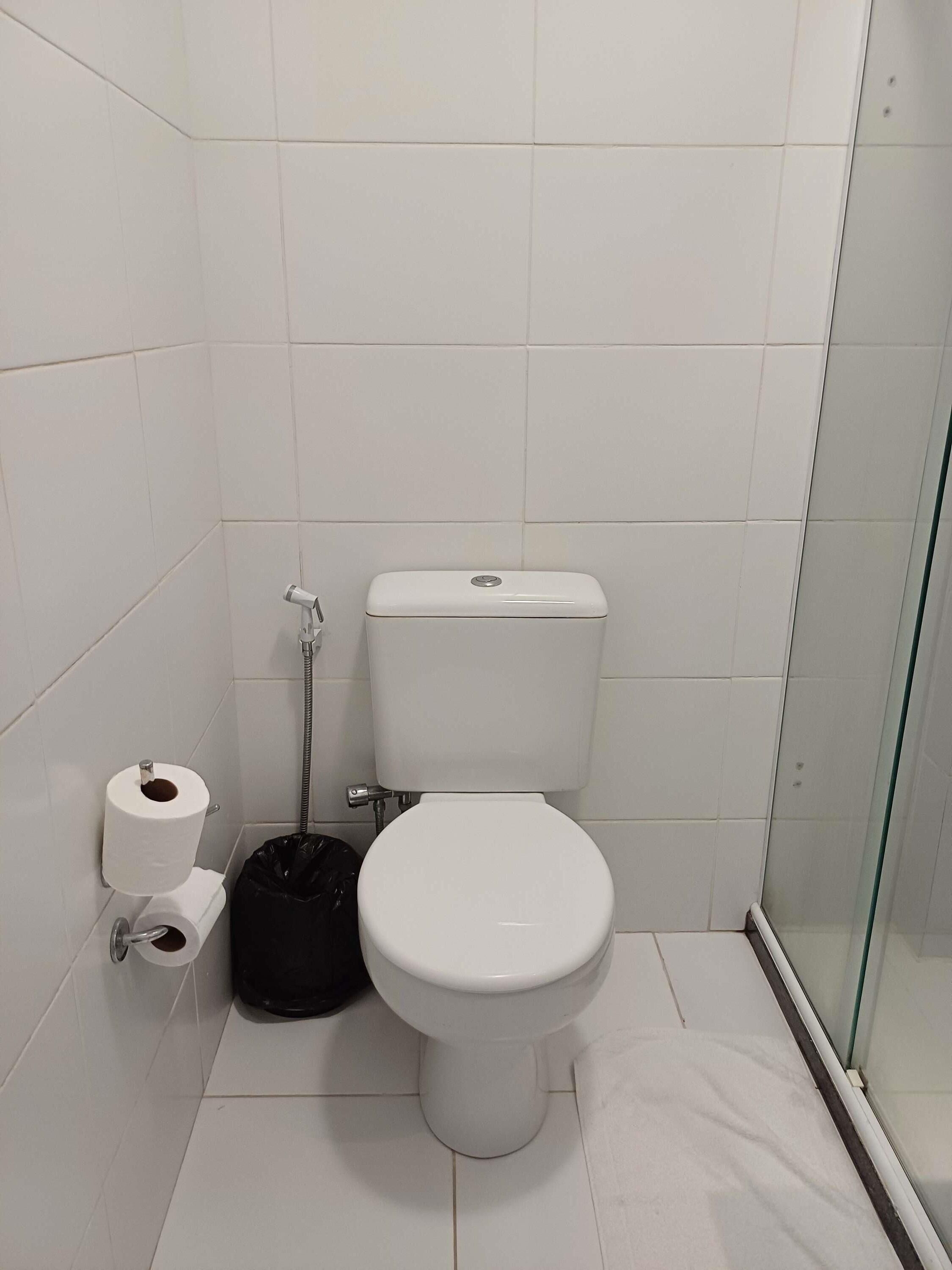 Un baño pequeño y limpio con inodoro, ducha y cabina de ducha con paredes de vidrio.