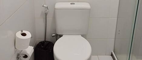Un baño pequeño y limpio con inodoro, ducha y cabina de ducha con paredes de vidrio.