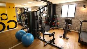 Un gimnasio con equipo de ejercicio, un espejo y una pared de ladrillo.