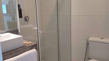 A modern bathroom with a glass-enclosed shower, a white sink, and a toilet.