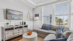 Ein Wohnzimmer mit Fernseher, einer Couch, einem Couchtisch und Blick ins Freie.