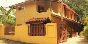 A yellow building with a brown roof and a gated entrance.