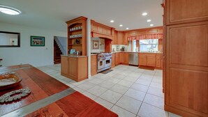 A spacious kitchen with wooden cabinets, a central island, and a dining area with a table and chairs. - 7 Mi to Bass Lake! Spacious 'Mudge Ranch Retreat' (Coarsegold)