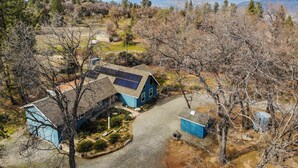 A two-story house with solar panels, a gravel driveway, and a surrounding wooded area. - 7 Mi to Bass Lake! Spacious 'Mudge Ranch Retreat' (Coarsegold)