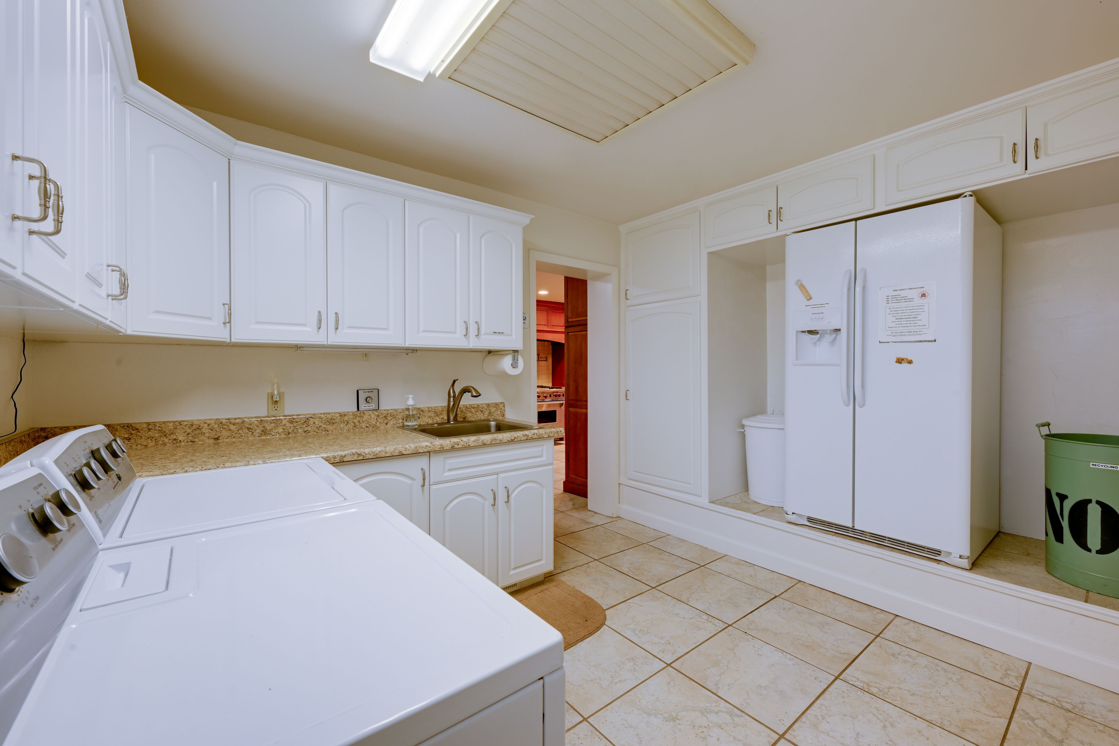 A laundry area with a washing machine, a sink, and a refrigerator.