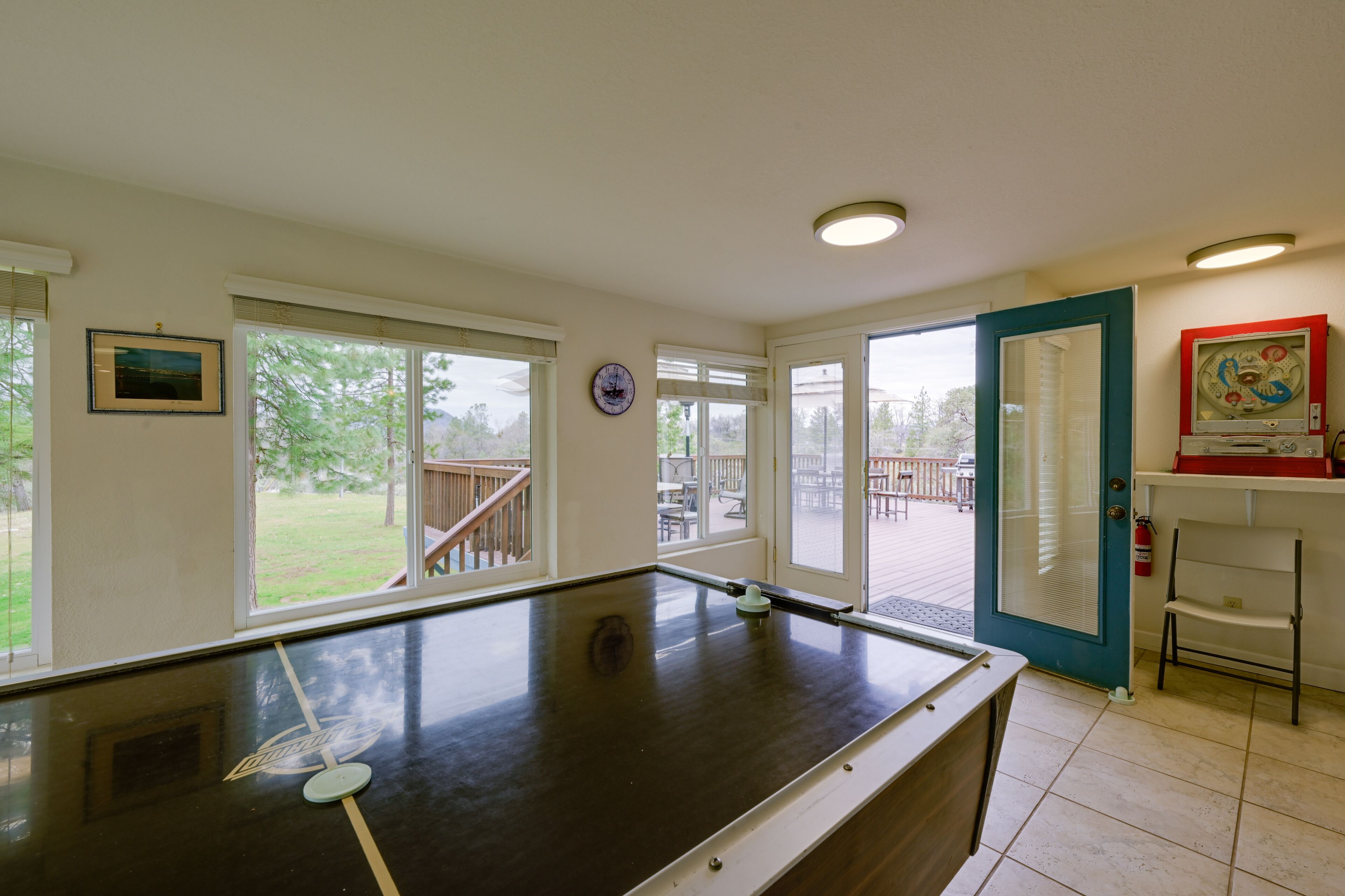 A pool table in a room with large windows, a door leading outside, and a small bar area.