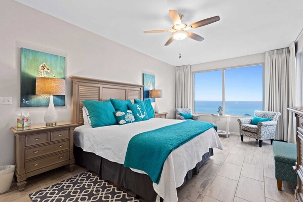 A bedroom with a large bed, a ceiling fan, a view of the ocean, a desk, and a chair. - Large End Unit 2 bed/ 2bath condo Beautifully renovated Beach Service Included Leeward Key 502 (Miramar Beach)
