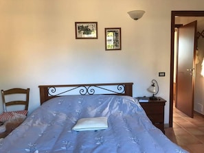 A bedroom with a bed, a chair, a bedside table with a lamp, and two framed pictures on the wall. - Apartment in Palazzo- Residence Giuly Rosselmini -Pool (Pieve Santa Luce)