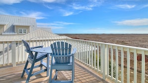 A deck with a table and two chairs, overlooking a barren landscape. - Beautiful Beach Home in Cinnamon Shore w/Gulf Peeks & Access to Amenities (Port Aransas)
