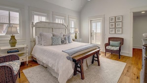 A bedroom with a large bed, a chair, a desk, and a ceiling fan. - Beautiful Beach Home in Cinnamon Shore w/Gulf Peeks & Access to Amenities (Port Aransas)