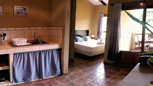 A room with a bed, a small kitchenette, and a view of the outdoors.