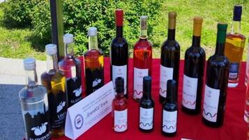 A table with various wine bottles and brochures, set outdoors with cars and greenery in the background.