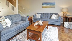 A living room with two grey sofas, a wooden coffee table, and a patterned rug. - Water Street Townhouses (Saugatuck)