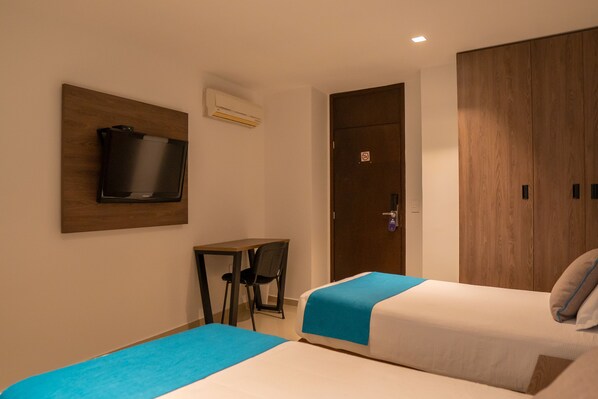 A hotel room with two beds, a desk, a chair, a television, and a wardrobe.