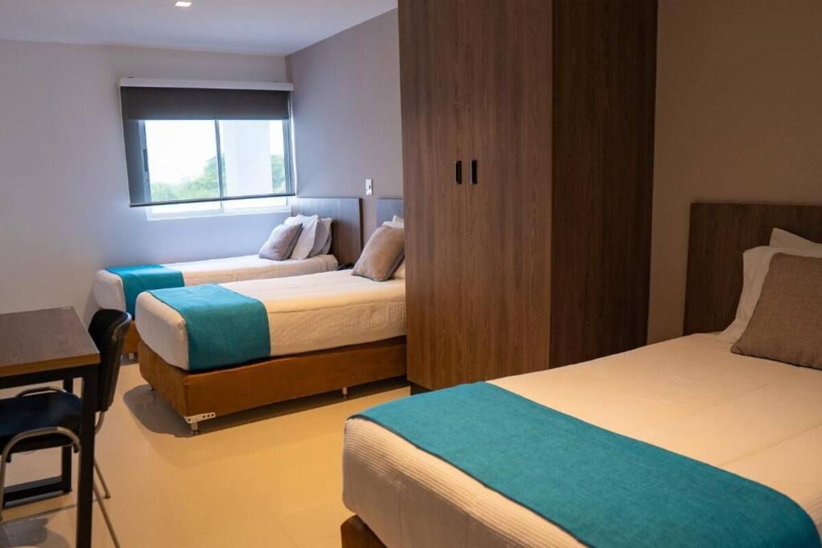 Hotellihuone, jossa on kaksi sänkyä, työpöytä ja ikkuna.