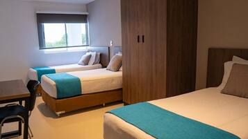 A hotel room with two beds, a desk, and a window.