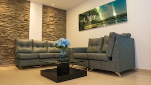 A modern living room with two grey sofas, a glass coffee table, and a vase of blue flowers. - Hotel San Gabriel (Barrancabermeja)