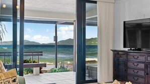 A modern living room with a large glass door leading to a balcony overlooking the sea.