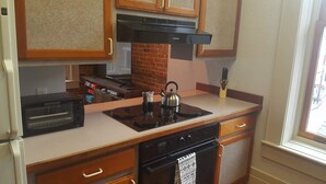 Una cocina compacta con horno integrado, microondas, tostadora y hervidor sobre la encimera.