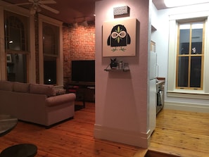 Ein Wohnzimmer mit Backsteinwand, Flachbildfernseher, Sofa und einem dekorativen Kunstwerk mit Eule.