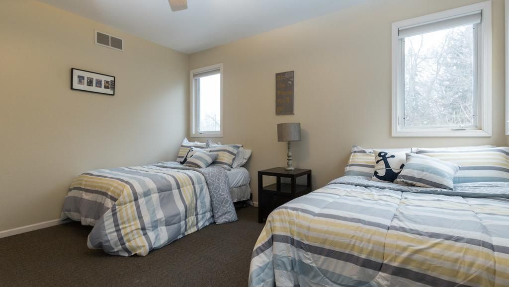 A bedroom with two beds, a small table, and a window.