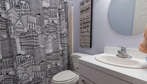 A bathroom with a patterned shower curtain, a toilet, a sink, and a mirror.