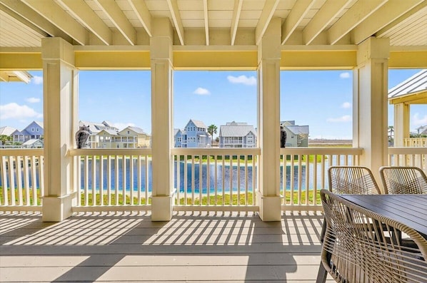 A covered outdoor area with a view of houses and a body of water.
