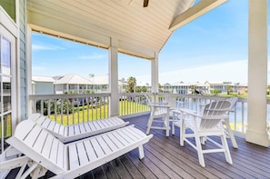 A covered outdoor area with white lounge chairs and a view of a residential area.