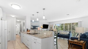 A spacious living area with a large island, a dark blue sofa, and a wicker coffee table. - Charming 2BR Condo Outrigger #4  by RVA (Longboat Key)