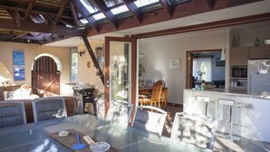 A spacious dining area with a glass table, surrounded by chairs, and a kitchen area with a refrigerator and microwave.