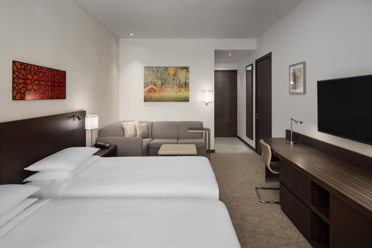 A hotel room with a large bed, a sofa, a desk, and a TV.