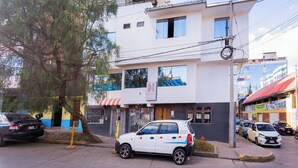 A two-story building with a white facade, a visible entrance, and parked cars in front. - Hermoza House Bed & Breakfast (Cusco)