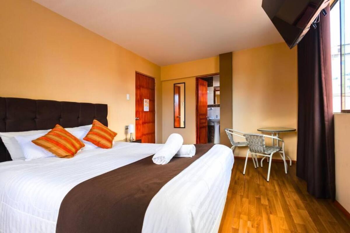 A hotel room with a bed, a small table, and a chair.