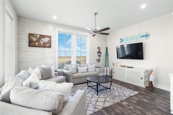 A modern living room with a sofa, coffee table, and a TV mounted on the wall. - Charming Home in Cinnamon Shore w/ Access to Many Resort-Like Amenities (Port Aransas)
