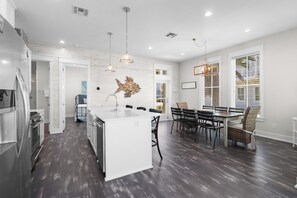 A modern kitchen with a central island, dark wooden flooring, and pendant lighting. - Charming Home in Cinnamon Shore w/ Access to Many Resort-Like Amenities (Port Aransas)