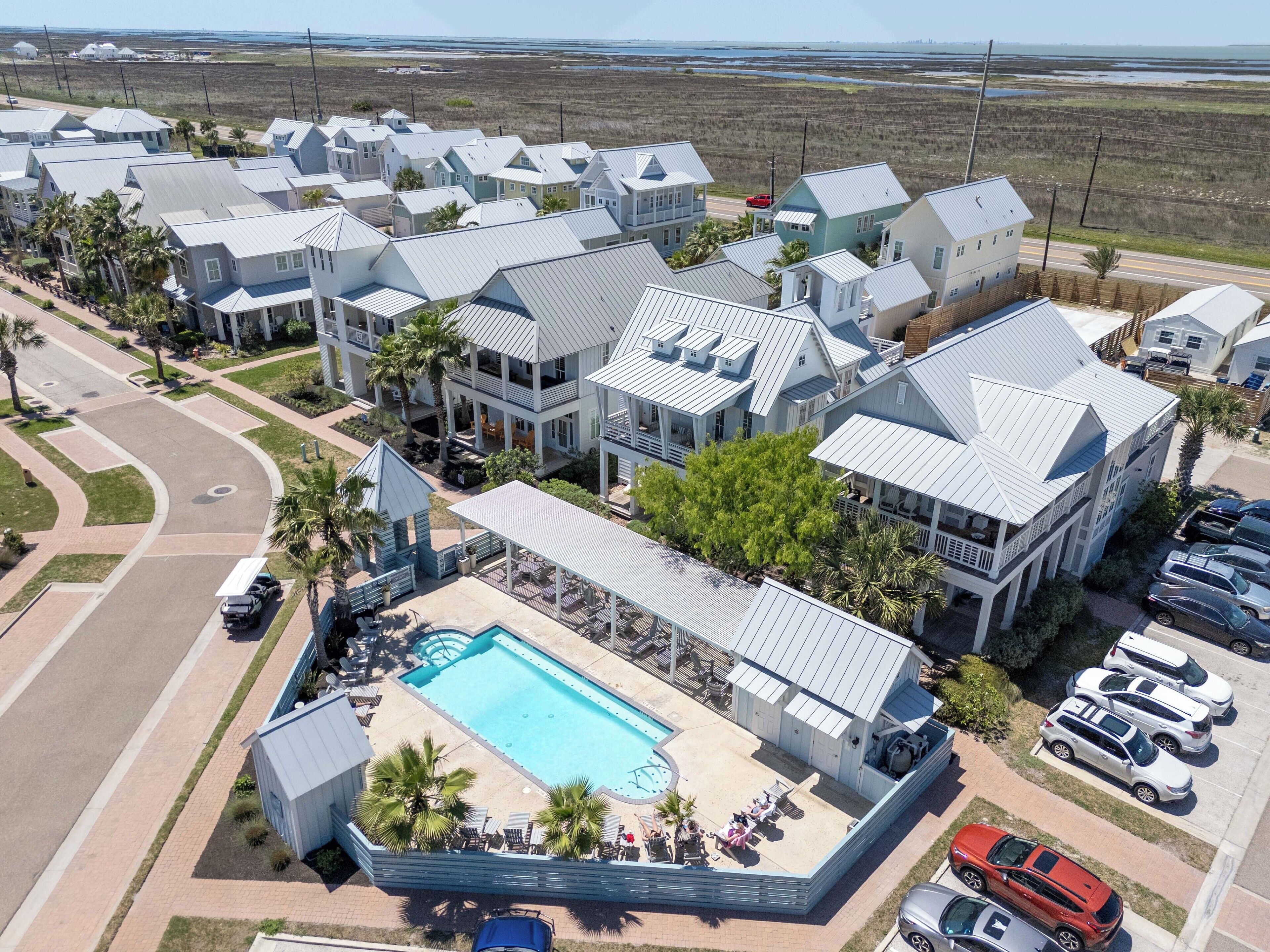 A residential area with multiple houses, a swimming pool, and parked cars.