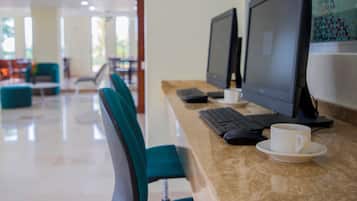 Uma mesa de escritório com dois monitores, um teclado, um rato e uma chávena sobre um pires.